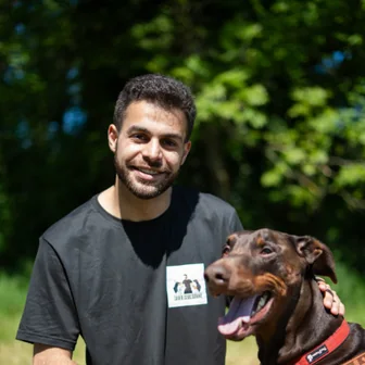 Ben Halimi, éducateur canin, accroupi à côté de Rey, son dobermann.